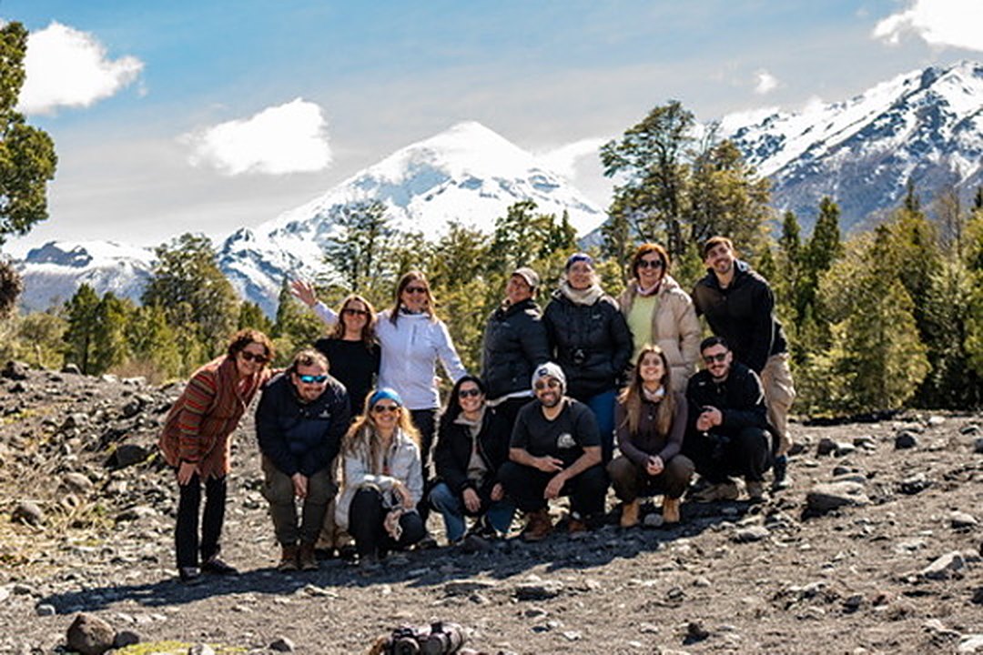 Grupo de viajeros sonriendo frente a un volcán nevado en la Patagonia